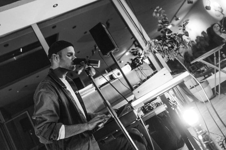 Singing at the microphone behind a keyboard, black and white