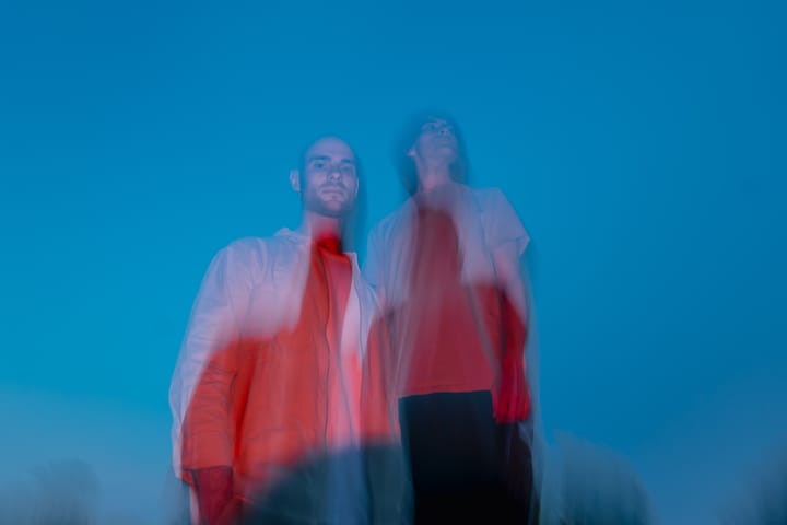 The duo in red against a blue sky, blurred in motion